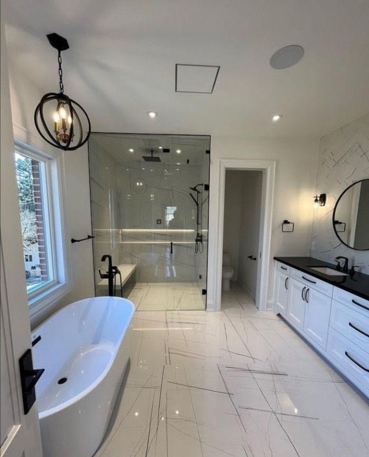 Renovated primary bathroom with marble-look tile and frameless glass shower in Vaughan